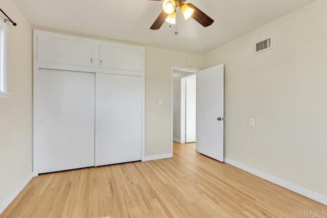 unfurnished bedroom featuring a ceiling fan, baseboards, visible vents, light wood finished floors, and a closet