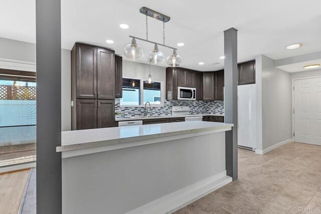 kitchen featuring a sink, white appliances, light countertops, decorative backsplash, and dark brown cabinets