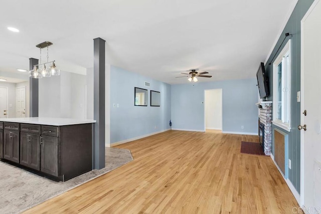 kitchen with baseboards, light wood-style flooring, a fireplace, light countertops, and open floor plan