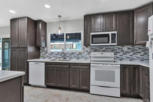 kitchen featuring white appliances, a sink, light countertops, dark brown cabinetry, and tasteful backsplash