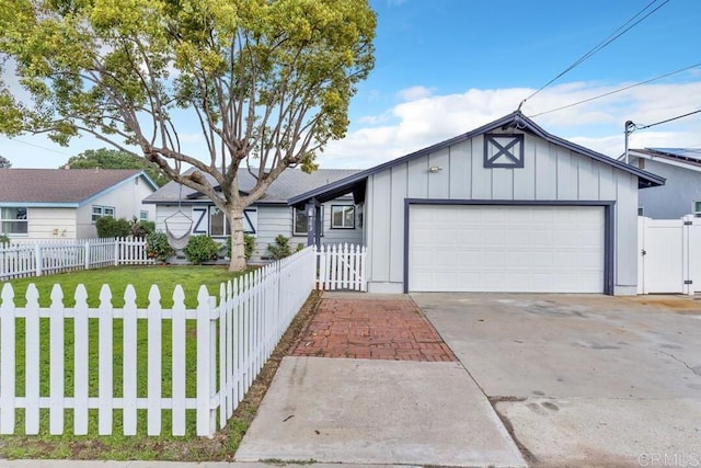 view of front of house featuring board and batten siding, a front lawn, a fenced front yard, a garage, and driveway