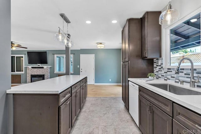 kitchen featuring dark brown cabinets, open floor plan, dishwasher, light countertops, and a sink