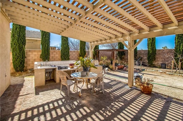 view of patio featuring a pergola, outdoor dining area, a fenced backyard, and a sink