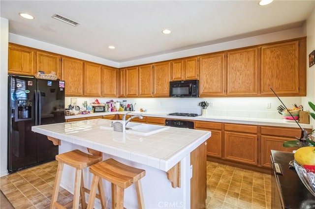 kitchen featuring black appliances, brown cabinets, visible vents, and a sink