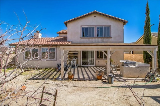 rear view of property with stucco siding, a wooden deck, a chimney, and a tile roof