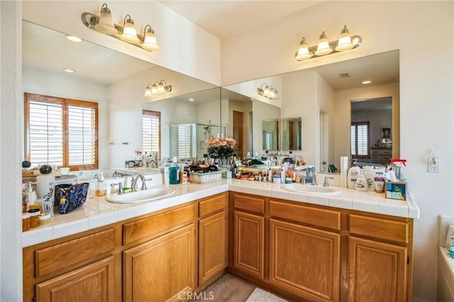 full bath featuring double vanity, visible vents, a stall shower, and a sink