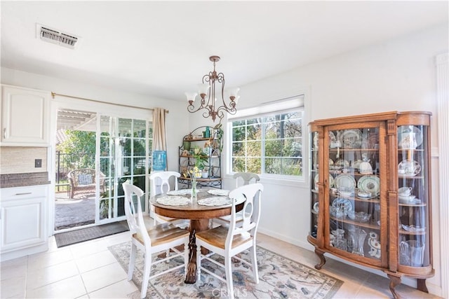 dining room featuring baseboards, light tile patterned flooring, visible vents, and a notable chandelier