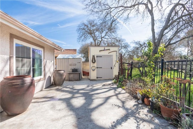 view of patio with a storage shed, fence, and an outbuilding