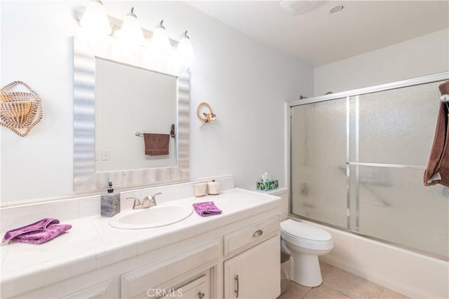 full bathroom featuring enclosed tub / shower combo, vanity, toilet, and tile patterned floors