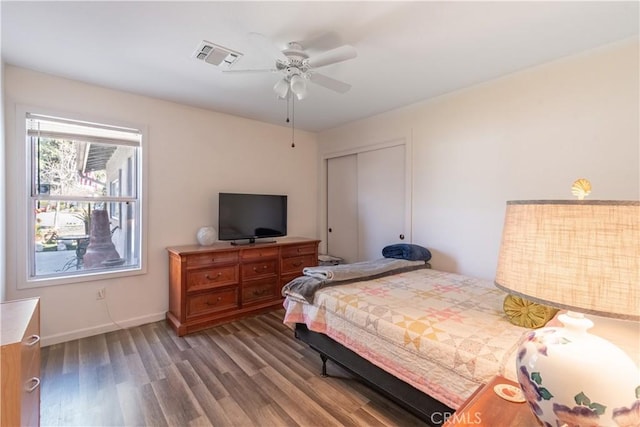 bedroom with a closet, visible vents, a ceiling fan, wood finished floors, and baseboards