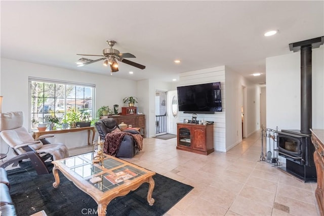 living area with a ceiling fan, recessed lighting, a wood stove, and light tile patterned floors