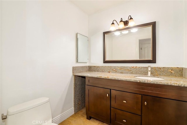 bathroom featuring double vanity, a sink, toilet, and baseboards