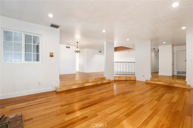 unfurnished room featuring light wood-style floors, visible vents, an inviting chandelier, and recessed lighting