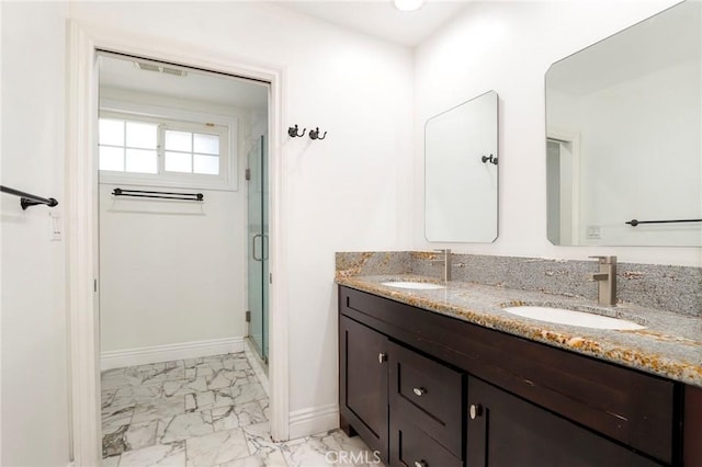 bathroom with marble finish floor, baseboards, a sink, and a stall shower