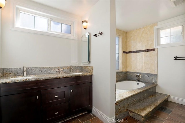 bathroom with visible vents, a sink, a garden tub, and double vanity