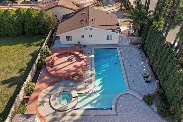 view of swimming pool with a fenced backyard, a pool with connected hot tub, and a lawn