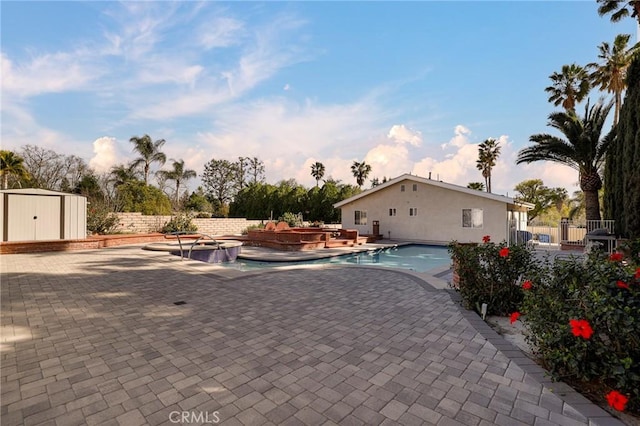 view of swimming pool with a patio, fence, a shed, an in ground hot tub, and an outdoor structure