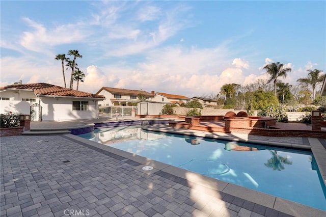 view of swimming pool featuring an outdoor structure, fence, a fenced in pool, a patio area, and a hot tub