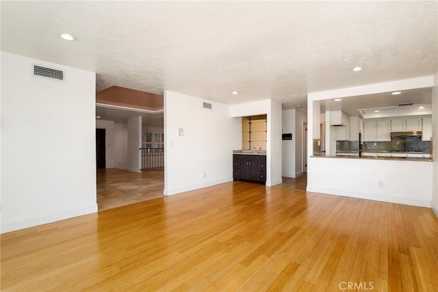 unfurnished living room featuring light wood-style floors, recessed lighting, visible vents, and baseboards