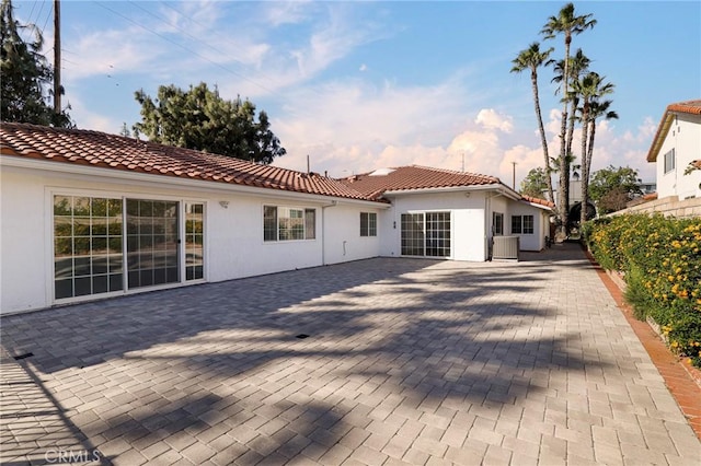 exterior space featuring a tiled roof, a patio area, fence, and stucco siding