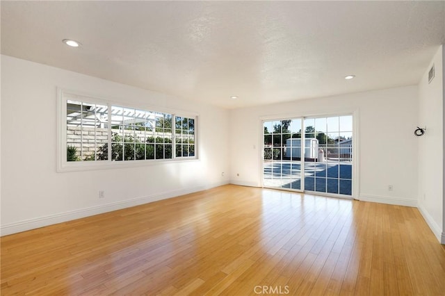 spare room with baseboards, a healthy amount of sunlight, visible vents, and light wood finished floors