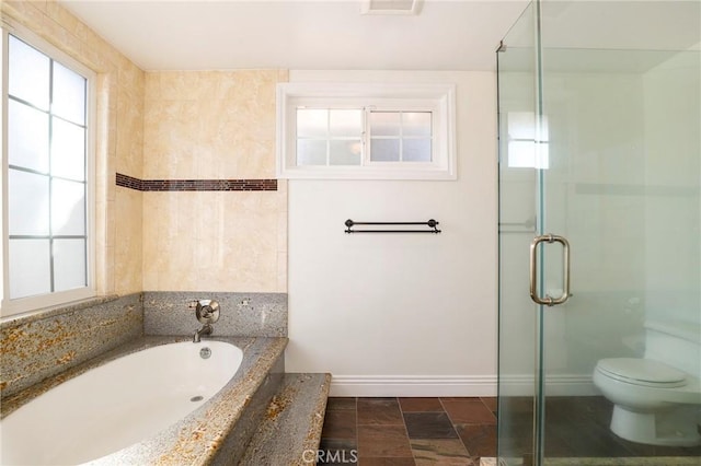 bathroom featuring toilet, a garden tub, a shower stall, and baseboards