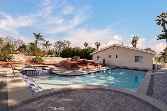 view of pool featuring a pool with connected hot tub, fence, and a patio