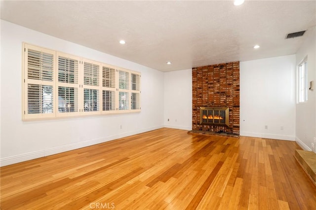 unfurnished living room with recessed lighting, visible vents, a brick fireplace, light wood-type flooring, and baseboards