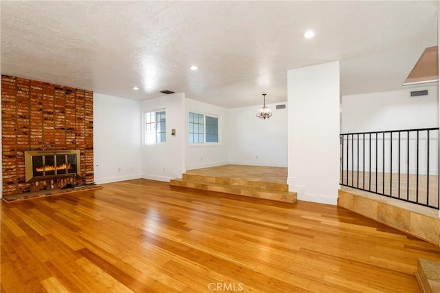 unfurnished living room with light wood-style floors, visible vents, a fireplace, and baseboards