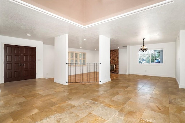 interior space featuring baseboards, a chandelier, and a textured ceiling