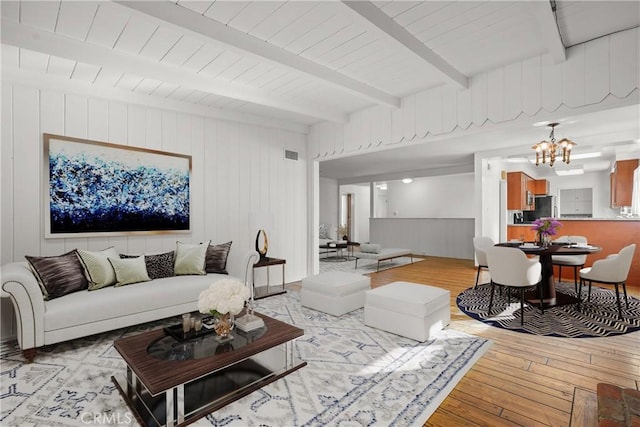 living room featuring visible vents, light wood-type flooring, beam ceiling, and a notable chandelier