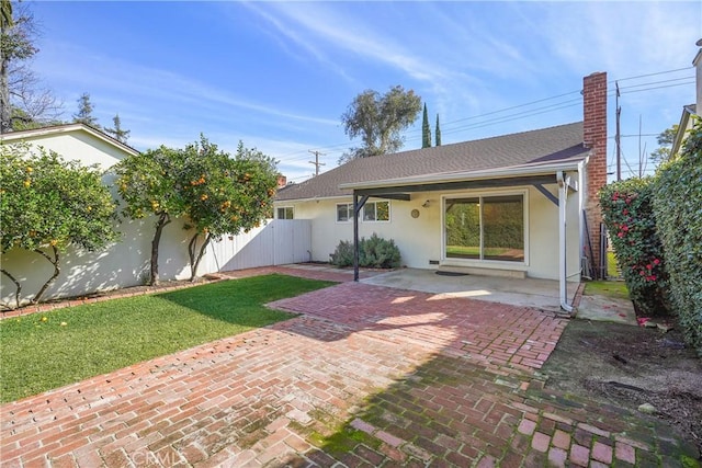 back of property featuring fence, roof with shingles, stucco siding, a chimney, and a patio area