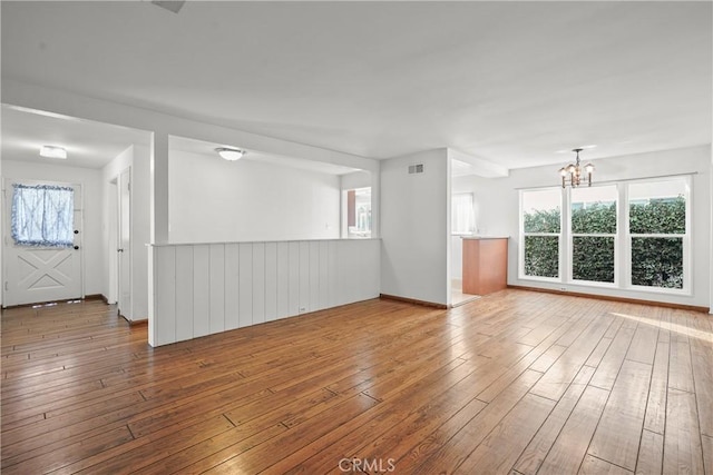 spare room featuring hardwood / wood-style flooring, visible vents, and a notable chandelier