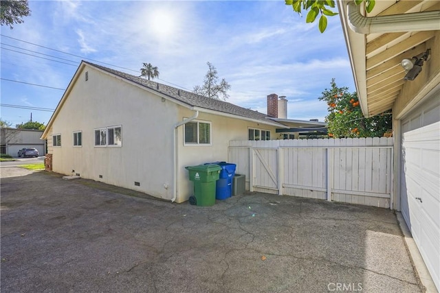 view of side of property with crawl space, a patio area, fence, and stucco siding