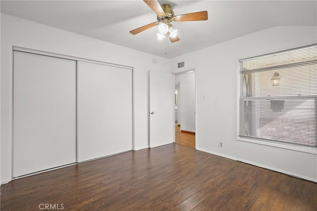 unfurnished bedroom featuring a closet, visible vents, a ceiling fan, wood finished floors, and baseboards