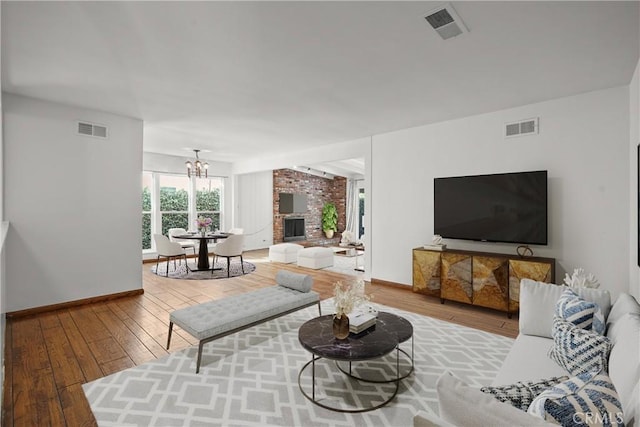 living area featuring a brick fireplace, wood-type flooring, and visible vents