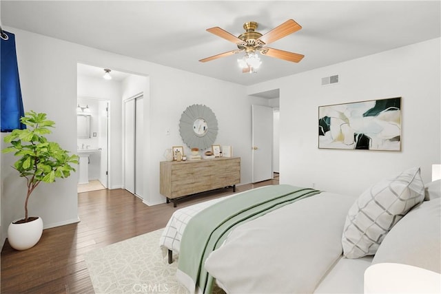 bedroom with ensuite bathroom, wood finished floors, visible vents, a ceiling fan, and a closet