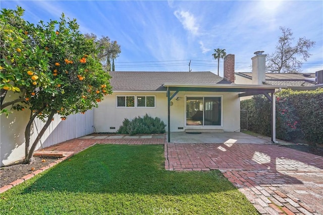 back of property featuring a lawn, a patio, a chimney, fence, and stucco siding