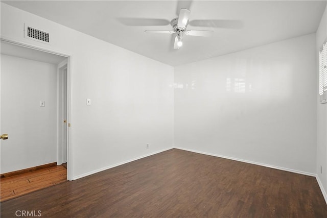 empty room with ceiling fan, dark wood-type flooring, visible vents, and baseboards