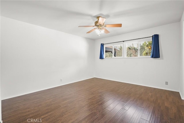 spare room with ceiling fan, dark wood finished floors, and baseboards