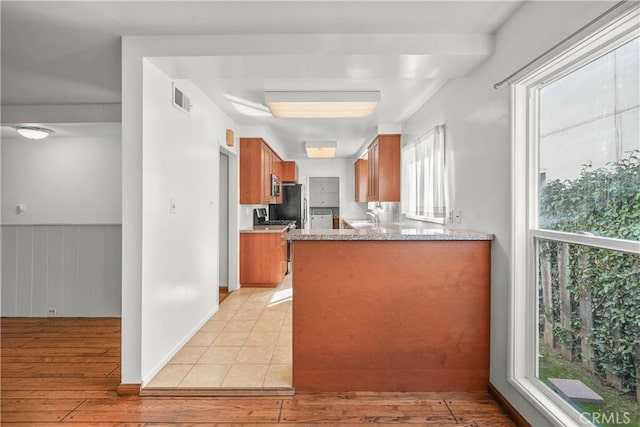 kitchen with light wood finished floors, brown cabinetry, appliances with stainless steel finishes, and visible vents