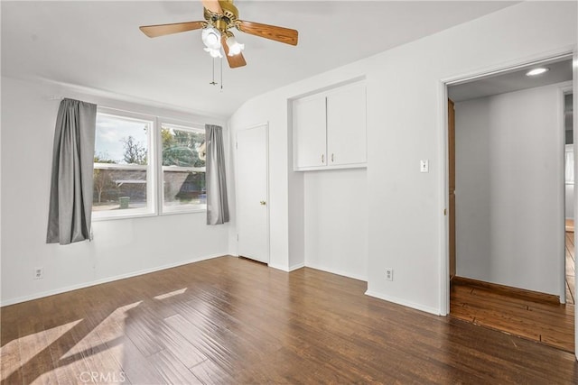 empty room featuring a ceiling fan, dark wood-style flooring, and baseboards