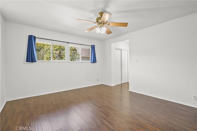 empty room featuring ceiling fan, wood finished floors, and baseboards