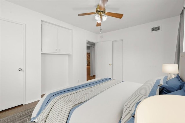 bedroom featuring wood finished floors, visible vents, and a ceiling fan