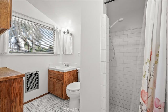 bathroom with heating unit, toilet, tiled shower, and vanity