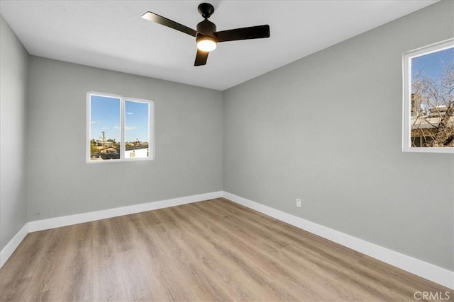 unfurnished room with ceiling fan, wood finished floors, and baseboards