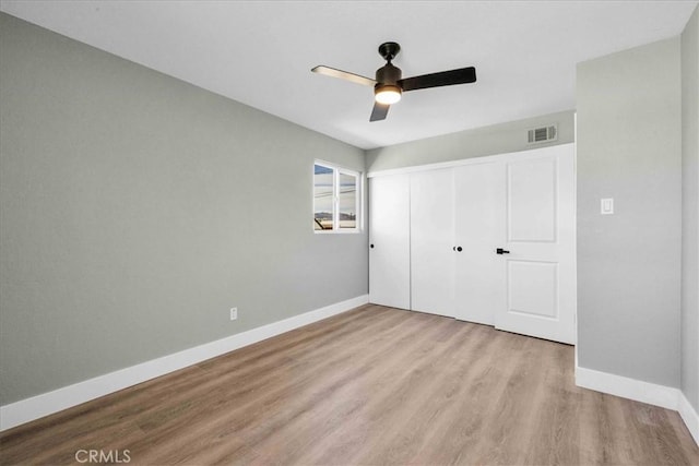 unfurnished bedroom featuring baseboards, visible vents, a ceiling fan, wood finished floors, and a closet