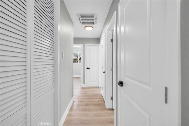 corridor featuring baseboards, visible vents, and light wood finished floors