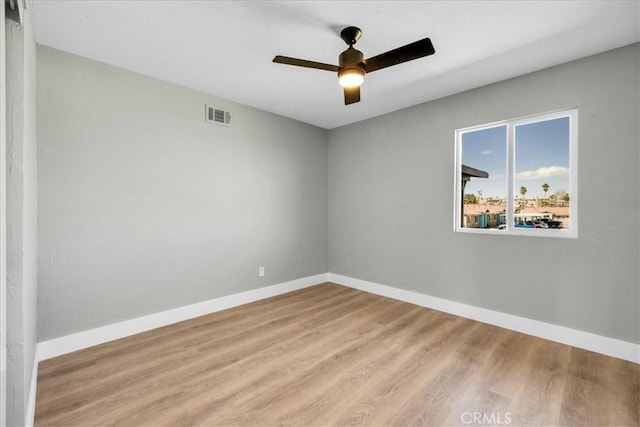 spare room featuring light wood-style floors, visible vents, baseboards, and ceiling fan