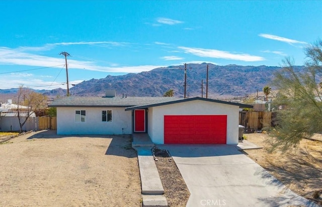 single story home featuring concrete driveway, a mountain view, an attached garage, and stucco siding